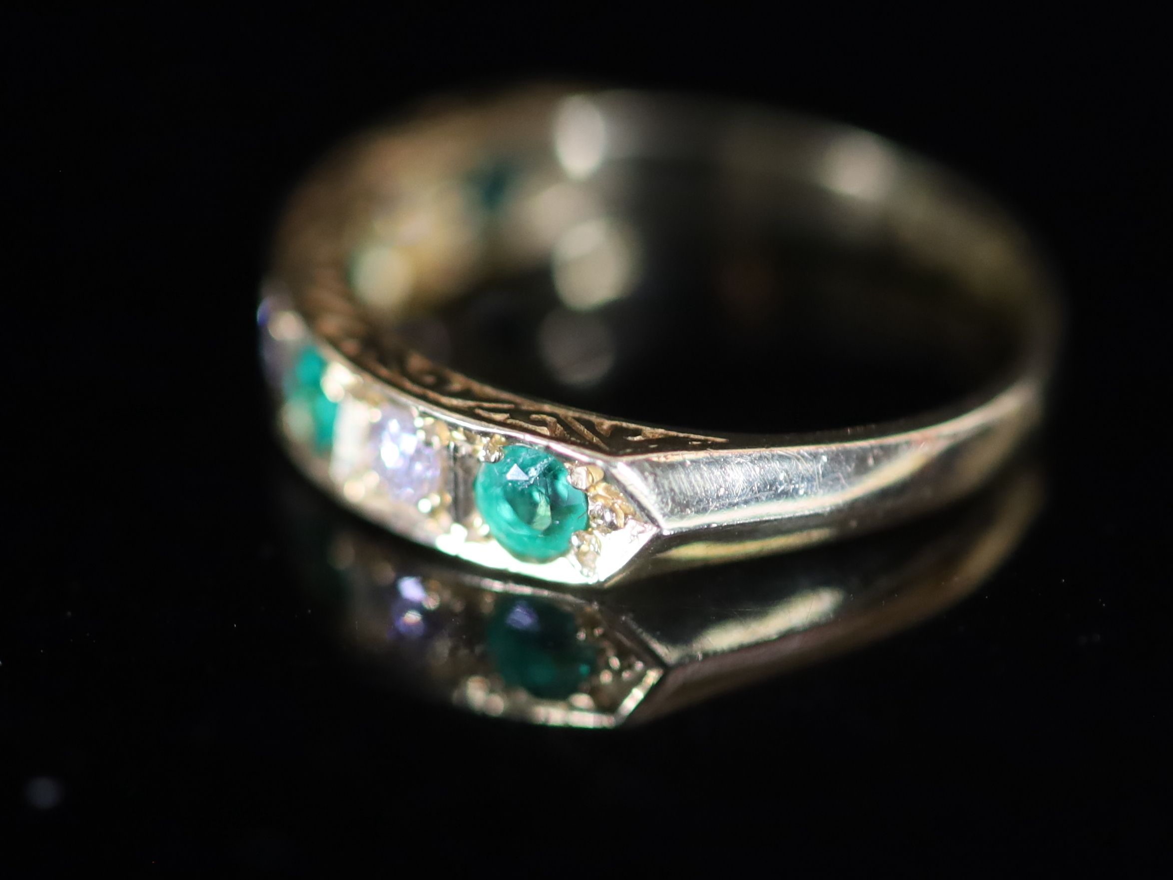 A modern 18ct gold, four stone emerald and three stone diamond set half hoop ring